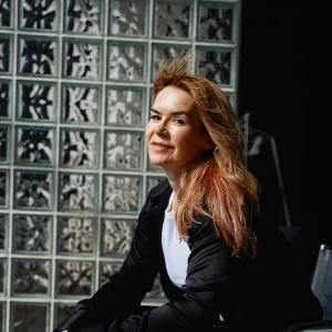 Sylwia Rytarowska, założycielka Digital Mistress, siedzi uśmiechnięta w nowoczesnym fotelu w swoim biurze, trzymając w ręku dokumenty.